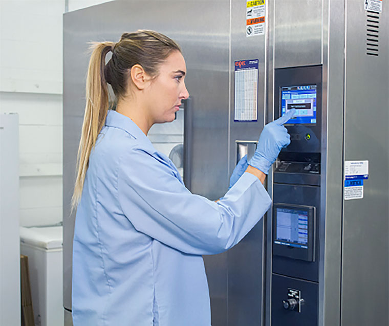 Girl in blue lab testing coat in front of temperature testing machine
